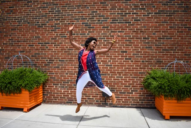 woman jumping in front of a brick wall