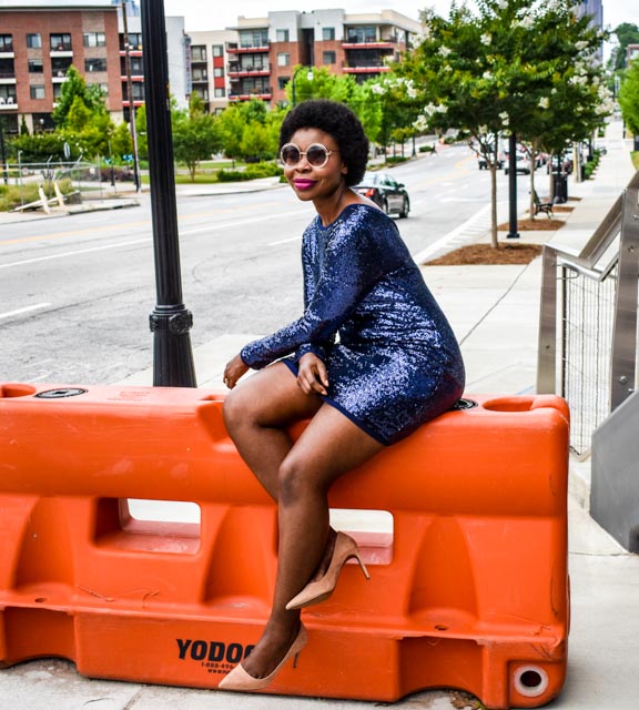 Woman sitting on orange barricade with sequin dress