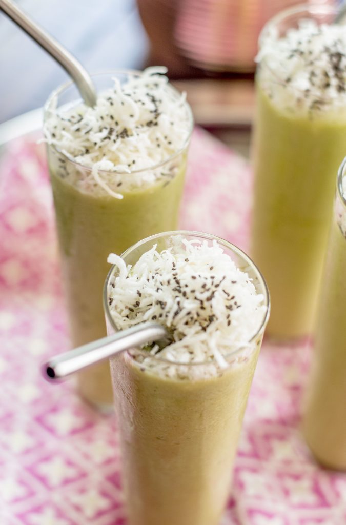 Green fruit shake in glass with a straw