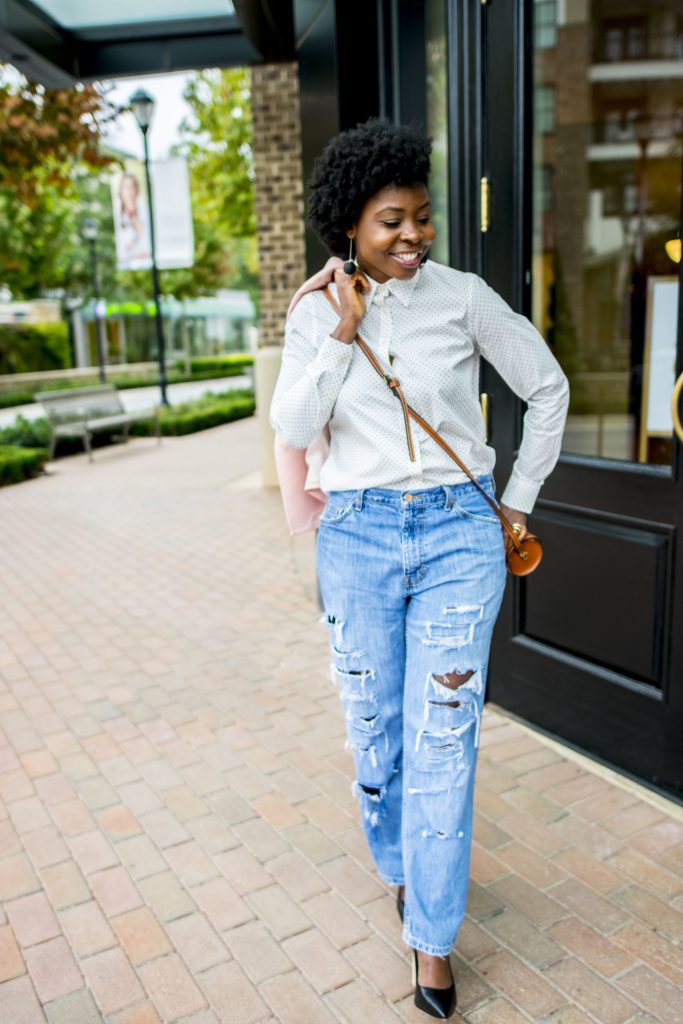 woman wearing distressed jeans holding a blazer over shoulder