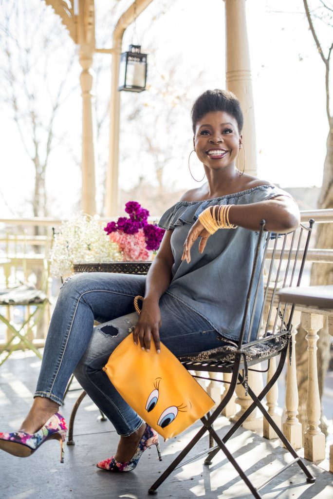 woman sitting on patio holding a yellow purse