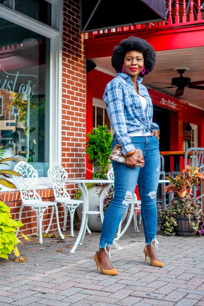 woman standing outside with an afro in a plaid shirt