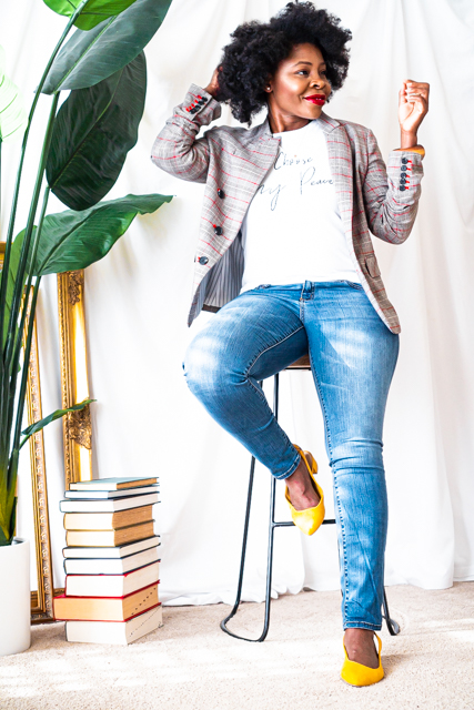 woman sitting on a barstool next to a tall plant touching her hair
